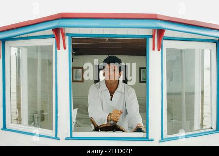 Homme adulte moyen tenant la barre d'un bateau à moteur Banque D'Images