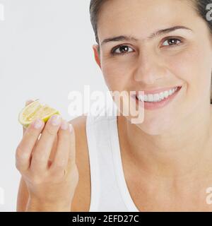 Portrait d'une jeune femme tenant une tranche de lime et souriant Banque D'Images