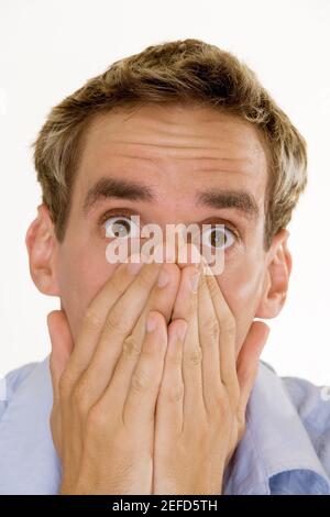 Portrait d'un jeune homme qui couvre sa bouche avec ses mains Banque D'Images
