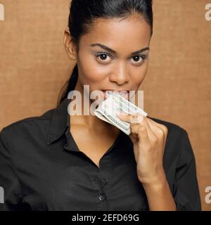 Portrait d'une jeune femme tenant une monnaie papier dans sa bouche Banque D'Images