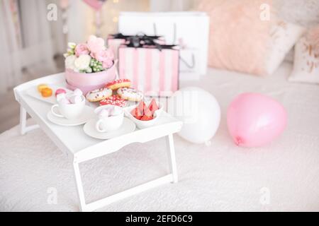 Fleurs et bonbons sur la table blanche et ballons sur le lit. Cadeau pour la Saint-Valentin ou le 8 mars ou pour la fête des mères ou l'anniversaire Banque D'Images