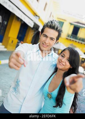 Portrait d'une adolescente avec un jeune homme pointant en avant et souriant Banque D'Images