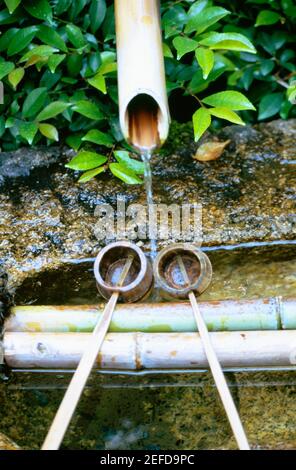 Vue à grand angle de l'eau qui coule d'une pipe de bambou dans un jardin de roche, Temple Ryoanji, Kyoto, Japon Banque D'Images