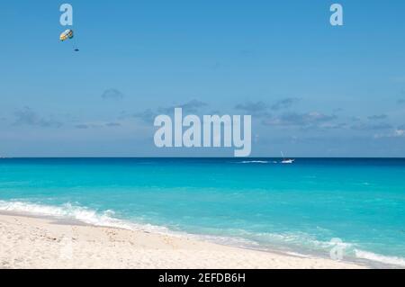 Parachute ascensionnel sur la mer tropicale près d'une plage exotique à Cancun, au Mexique. En été, activités de loisirs et d'amusement. En arrière-plan le ciel bleu et quelques c Banque D'Images