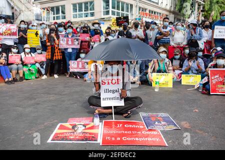 Un manifestant est vu assis au milieu de la route, portant un écriteau indiquant « arrêter illégalement » et tenant un parapluie pour la protéger du soleil pendant la manifestation du coup d'État militaire.UNE foule massive s'est emmenée dans les rues qui bloquent la route de Sule Pagoda, Une route importante à Yangon pour protester contre le coup d'État militaire et demander la libération d'Aung San Suu Kyi. L'armée du Myanmar a détenu le conseiller d'État du Myanmar Aung San Suu Kyi le 01 février 2021 et a déclaré l'état d'urgence tout en prenant le pouvoir dans le pays pendant un an après avoir perdu les élections contre la Ligue nationale pour Democra Banque D'Images