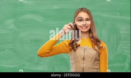 fille étudiante regardant par loupe à l'école Banque D'Images