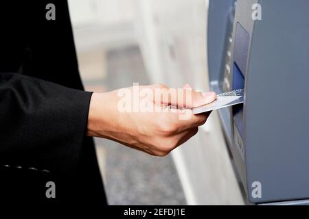 Gros plan d'une main de personÅl qui insère une carte de crédit dans Un ATM Banque D'Images