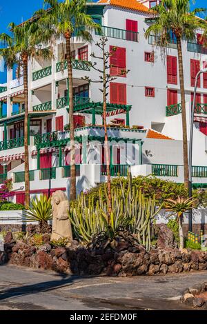 Boulevard à Playa de Las Americas avec un bâtiment avec des volets de fenêtre rouges, cactus, Ténérife, île des Canaries Banque D'Images