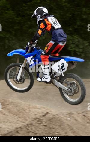 Profil latéral d'un motocross effectuant un saut sur un moto Banque D'Images
