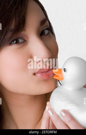 Portrait d'une jeune femme embrassant un canard jouet Banque D'Images