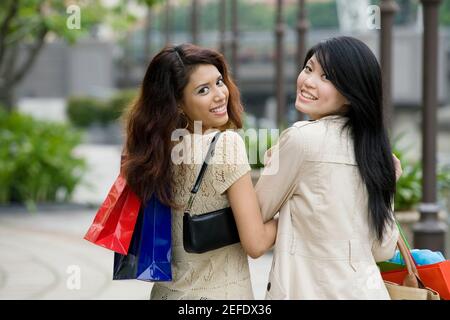 Portrait de deux jeunes femmes carrying shopping bags and smiling Banque D'Images