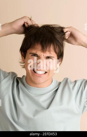 Portrait d'un jeune homme tirant ses cheveux Banque D'Images