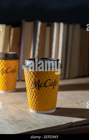 Ukraine, Kiev - 17 février 2021 : verre de café jaune de McDonald's. Verre en papier boisson McCafe. Coupe en offee sur table avec ombres. Menu dans fastfood Banque D'Images