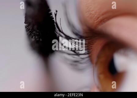 Close-up of a young woman applying mascara Banque D'Images