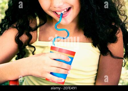 Gros plan d'une fille tenant une tasse jetable et buvant avec une paille Banque D'Images