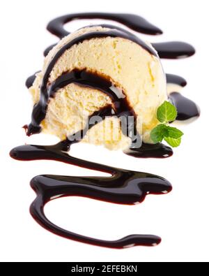 Une seule cuillère à crème glacée à la vanille avec sauce au chocolat et menthe feuille isolée sur fond blanc Banque D'Images