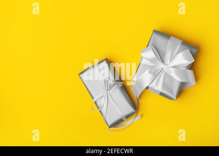 Cadeaux gris minimalistes tendance sur fond jaune. Couleurs de 2021. Joyeux Noël, Saint-Valentin, joyeux anniversaire et autres concepts de fêtes. Banque D'Images