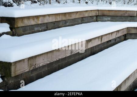 grandes marches en bois dans un jardin en hiver recouvert de neige Banque D'Images