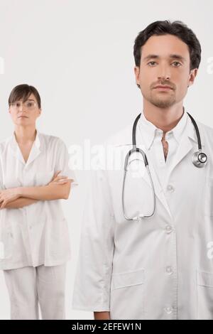 Portrait d'un médecin masculin avec une femme médecin debout en arrière-plan Banque D'Images