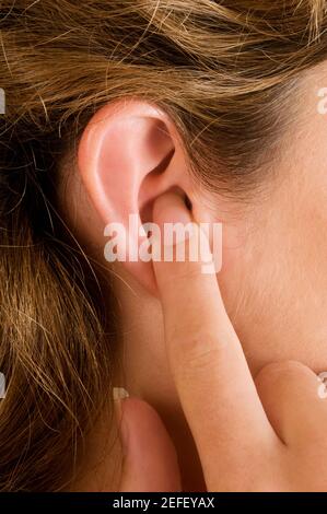 Gros plan d'un jeune doigt de femme dans son oreille Banque D'Images