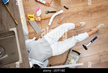 Femme fixing évier de cuisine. Femme de ménage travaillant sous la cuisine Banque D'Images