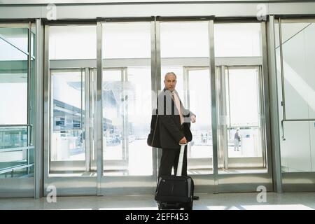 Profil latéral d'un homme d'affaires tirant ses bagages à un aéroport Banque D'Images