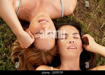 Vue en grand angle de deux femmes adultes de taille moyenne l'herbe avec les yeux fermés Banque D'Images