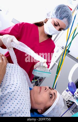 Femme chirurgien mettant un masque d'oxygène sur une patiente face Banque D'Images