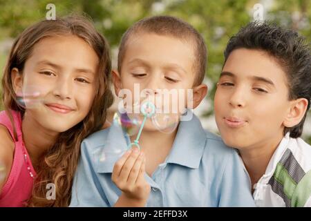 Portrait d'un garçon soufflant des bulles avec sa sœur et frère Banque D'Images