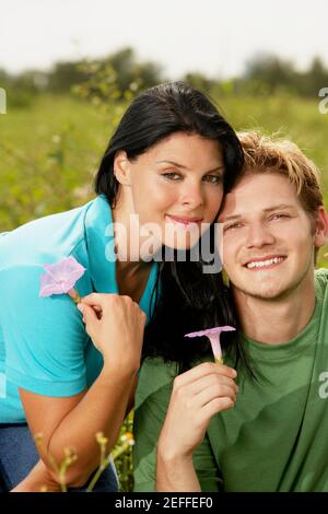 Portrait d'un jeune homme et d'une jeune femme tenant fleurs Banque D'Images