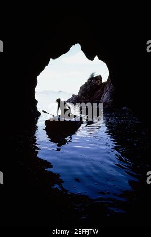 Un homme ramer un canoë vu à travers la grotte, Treasure Island, Iles Vierges Banque D'Images