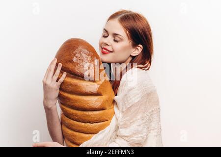 femme tenant un grand pain et un maquillage brillant dans elle Modèle de vêtement léger pour les mains Banque D'Images