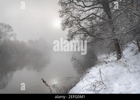 Soleil traversant la brume au-dessus de la rivière Teviot Neige d'hiver aux frontières écossaises Banque D'Images