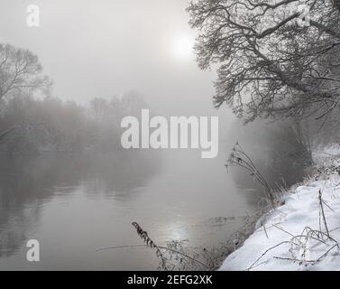 Soleil traversant la brume au-dessus de la rivière Teviot Neige d'hiver aux frontières écossaises Banque D'Images