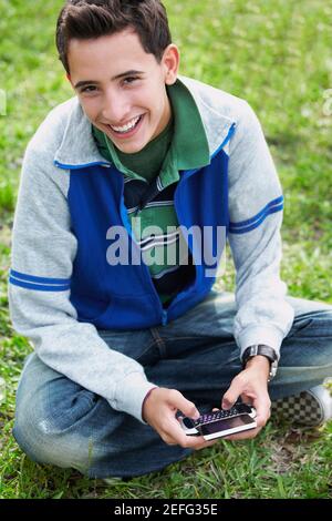 High angle view of a Teenage boy smiling et l'utilisation d'un téléphone mobile Banque D'Images