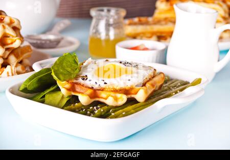 Petit-déjeuner le matin. Gaufres fraîches maison avec omelette, feuilles d'épinards et asperges Banque D'Images