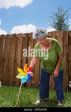 Senior woman holding a pinwheel dans une arrière-cour et smiling Banque D'Images