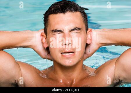 Close-up d'un jeune homme aux projections d'eau dans une piscine Banque D'Images