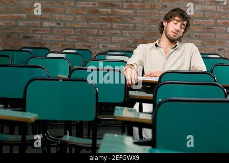 Un jeune homme qui fait la sieste dans une salle de classe Banque D'Images