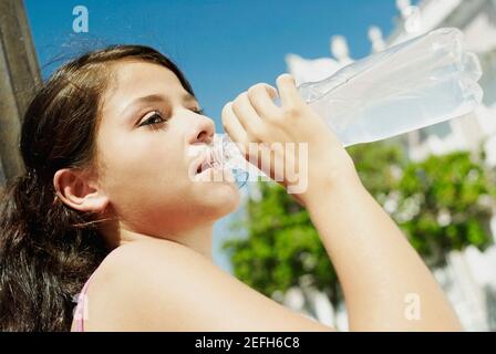 Profil latéral d'une adolescente qui boit de l'eau d'un bouteille Banque D'Images