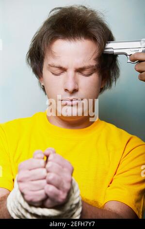 Gros sur un jeune homme les mains attachées avec la corde et un revolver sur sa tête Banque D'Images