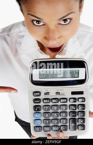 Portrait d'une femme d'affaires tenant une calculatrice avec sa bouche ouvrir Banque D'Images