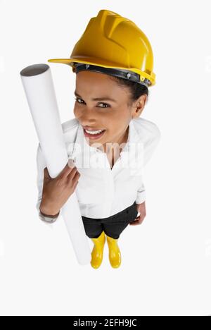 Vue en grand angle d'une femme architecte tenant un plan et souriant Banque D'Images