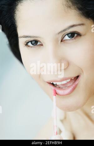 Gros plan d'une jeune femme appliquant un revêtement de lèvre Banque D'Images