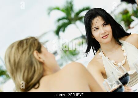 Deux jeunes femmes assises à la table avec des lunettes de vin devant eux Banque D'Images