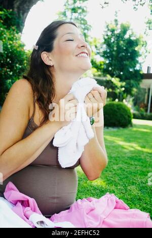 Jeune femme tenant des vêtements de bébé Banque D'Images