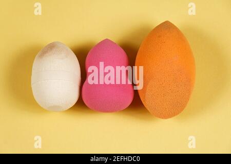 Éponges mousse colorées maquillage accessoire de beauté dans une rangée sur fond jaune Banque D'Images