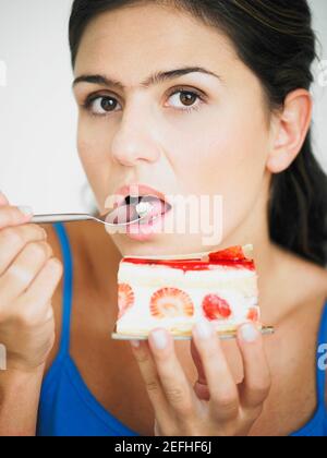 Jeune femme mangeant un gâteau avec une cuillère Banque D'Images