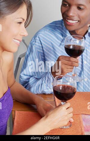 Gros plan d'un jeune couple assis et tenant des lunettes de vin Banque D'Images