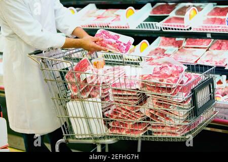 Vue en coupe du milieu d'un homme mettant de la viande emballée dans un panier Banque D'Images